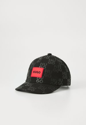 Casquette noire avec un motif répétitif du logo "HUGO" en gris foncé, et un patch carré rouge affichant "HUGO" en texte noir.