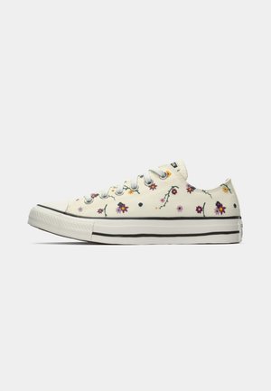 Weiße Low-Top-Sneaker mit bunten kleinen Blumenmustern und weißen Schnürsenkeln, von der Innenseite auf einem schlichten Hintergrund betrachtet.