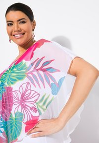 Lettfærdig, gennemsigtig cover-up med livlige blomsterprints i pink, grøn og blå på en hvid baggrund. Glat tekstur med blød drapering.