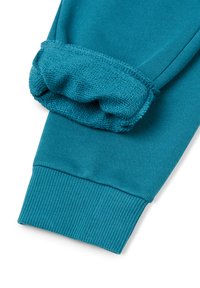 Tyrkysové dlouhé rukávy s manžetami ukazují jak vnitřní fleecovou podšívku, tak vnější hladkou pleteninu, zdůrazňující kontrast textur a detaily šití.