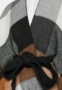 Envuelta con un patrón en tonos negro, gris y naranja quemado; presenta un acabado texturizado y un detalle de cinturón negro atado en la cintura.