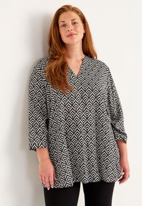 Black and white patterned blouse with a V-neck and three-quarter sleeves, featuring a geometric design on lightweight fabric.