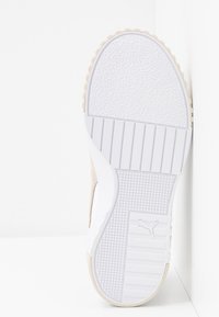 Semelle de basket en caoutchouc blanc avec motifs texturés et logo Puma, présentée sur un fond blanc.