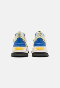 Sneaker sportive con un design a più strati, caratterizzati da dettagli bianchi, blu e gialli; materiale testurizzato e suola nera imbottita.