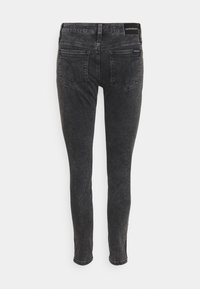 Jeans de mezclilla negra ajustados con una sutil textura desgastada, que cuentan con dos bolsillos traseros y una cinturilla con marca en la parte posterior.
