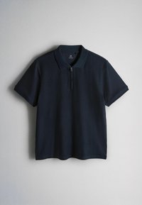 Donkerblauw polohemd met korte mouwen, een kraag en een voorrits, plat gelegd op een lichtegrijze achtergrond.