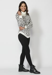 Leopardmönstrad tröja med vit polokrage, tillsammans med svarta smala jeans och svarta snörkängor. Slät textur, avslappnad passform.