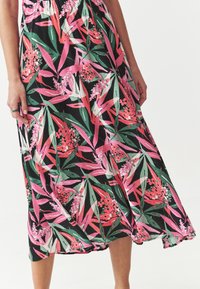 Robe d'été fleurie avec un fond noir et des motifs de feuilles roses et vertes. Fabriquée en tissu léger avec une silhouette fluide.