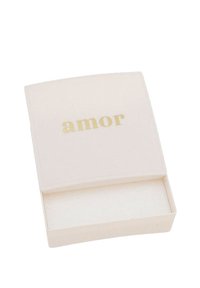 Scatola rettangolare di colore crema con una superficie liscia e un'iscrizione dorata "amor" sul coperchio. Contiene un compartimento vuoto all'interno.