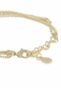 Guldmetallarmband som har en kombination av släta och texturerade led, med låsning och en liten charm-tag.