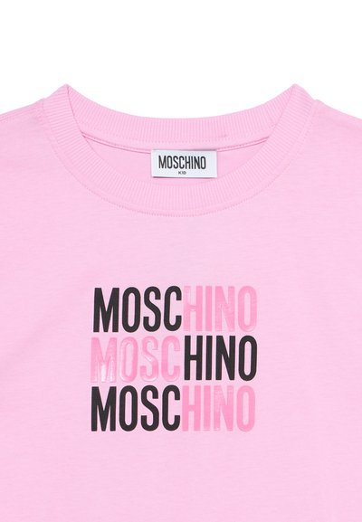 Ροζ παιδικό μπλουζάκι με ριμπ γύρο λαιμόκοψη και επαναλαμβανόμενο λογότυπο "MOSCHINO" σε εναλλασσόμενα μαύρα και ροζ γράμματα στο μπροστινό μέρος.