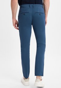Chinos blu per uomo con una vestibilità slim, realizzati in tessuto misto cotone, con tasche posteriori con chiusura a bottone e gambe affusolate.