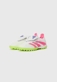 White athletic shoes with pink and purple accents, a textured surface, and bright green soles. Features a velcro strap for secure fit.