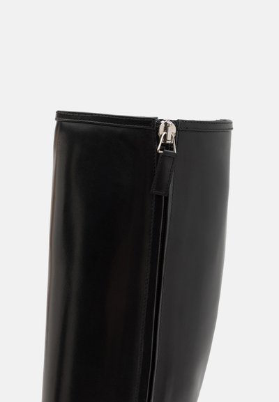 Bota de cuero negro hasta la rodilla con un acabado brillante. Presenta una cremallera lateral con herrajes plateados y un borde superior liso y sin costuras.