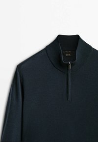 Dunkelblauer Zip-Hals-Pullover mit geripptem Kragen und Bündchen, aus weichem Strickmaterial hergestellt. Verfügt über einen Viertelreißverschluss am Hals.