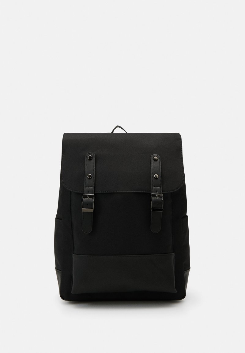 Zaino nero con chiusura a pattina, due spallacci regolabili e dettagli in pelle. Presenta una superficie liscia e una forma rettangolare semplice.