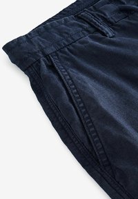 Navy blue waistband shorts with gathered detailing, made of lightweight fabric, featuring stitching accents and a smooth texture.