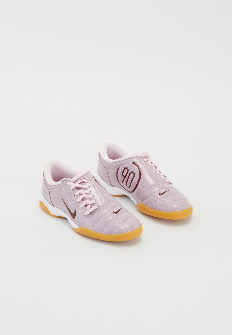 Purple synthetic athletic shoes with a textured upper, pink laces, a visible red '90' detail, and a gum rubber sole.