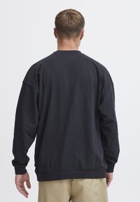 Dark blue sweatshirt with a relaxed fit, round neckline, and long sleeves. Features ribbed cuffs and hem with a smooth texture.