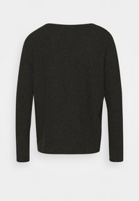 Dlouhý rukáv v tmavě šedé látce, s širokým výstřihem a volným střihem, se štěrbinami po stranách pro větší pohyb a pohodlí.