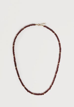 Ogrlica s malim okruglim tamnocrvenim perlicama izmiješanim s malim zlatnim razdjelnim perlicama i zlatnim lančićem s kopčom na bijeloj pozadini.