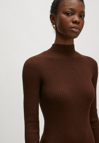 Bruine geribbelde lange mouwen top met hoge hals. Heeft een slim fit silhouet en een gestructureerde stof, die de strakke lijnen en een gladde afwerking benadrukt.
