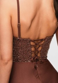 Vue de dos d'une robe marron avec des bretelles réglables et un dos style corset à sequins et lacets.