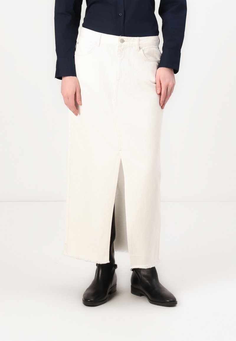 Hvit denim maxi-skjørt med slisse foran, frynset kant og sidelommer. Brukt med svarte ankelboots og en marineblå skjorte med knapper.