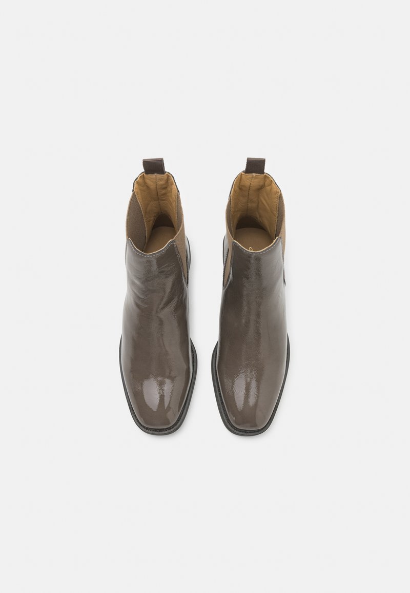 Braune Leder-Stiefeletten mit einem eleganten Finish, spitzem Zeh und elastischen seitlichen Einsätzen. Das Innere ist mit einem kontrastierenden beigen Stoff gefüttert.