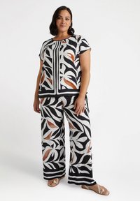 Two-piece outfit with a relaxed fit. Features a black and white leaf pattern with copper accents. Made from lightweight fabric.