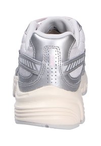 Zapatilla deportiva blanca con una parte superior de malla texturizada, acentos plateados, diseño transpirable y suela acolchada de color blanco roto.
