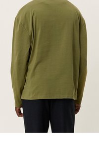 Langarmshirt aus olivgrünem Baumwollstoff, lässiger Schnitt mit abgesenkten Schultern, gerippten Bündchen und geradem Saum. Weiche Textur, kein Muster.