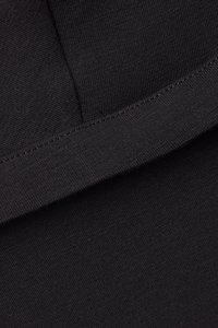 Närbild på svart tyg med en slät textur. Har en enkel design med en synlig söm vid kanten. Materialet verkar elastiskt och mjukt.