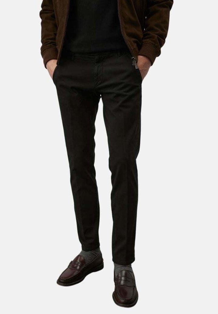 Pantaloni neri in tessuto liscio, design affusolato, tasche frontali e zip. Abbinati a mocassini scuri e calzini grigi.