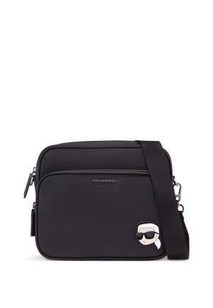 Black nylon crossbody bag with a smooth texture, featuring a front zip pocket and a Karl Lagerfeld cartoon logo accent. Adjustable strap included.
