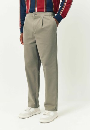 Light gray trousers with a smooth texture, featuring side pockets, a button closure, and subtle pleats at the front. Paired with white sneakers.