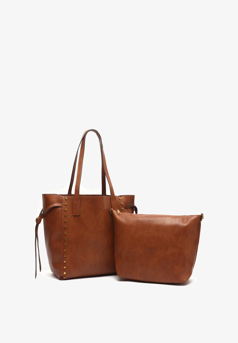 Due borse in pelle marrone: una tote più grande con borchie decorative e due manici, e una pochette più piccola con chiusura zip e superficie liscia.
