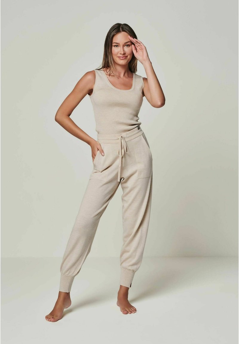 Beige geripptes Tank-Top kombiniert mit passenden Jogginghosen mit Kordelzug, die über Seitentaschen und schmale Bündchen verfügen. Glattes, leichtes Strickmaterial.