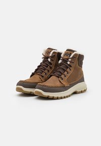 Bottes en cuir marron et tissu avec doublure en fourrure, design à lacets, détails cousus et semelle en caoutchouc beige épaisse pour une meilleure traction.