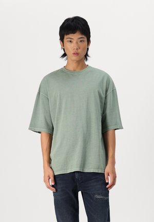 Green cotton t-shirt with a crew neck, short sleeves, and a relaxed fit. Subtle texture and stitching details complement its casual design.