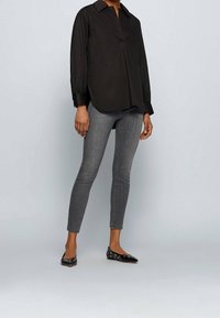 Svart långärmad skjorta med krage och sidofickor, i kombination med grå skinny jeans och svarta ballerinas med metalliska detaljer.