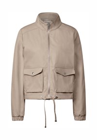 Veste courte beige, tissu lisse, col montant, fermeture éclair devant, deux grandes poches à boutons, cordon ajustable à l'ourlet.