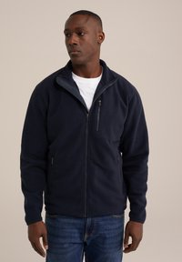 Tumesinine fliiskasukas kõrge kaelusega, täispiksegedusega ja kahe tõmblukuga küljetaskuga. Pehme tekstuur ja lõdvestatud istuvus.