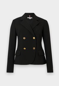 Črn blazer z dvojno zapenjanjem z zlatimi gumbi, izreznimi reverji in sprednjimi žepi. Ima vezen, našit na levi prsni del.