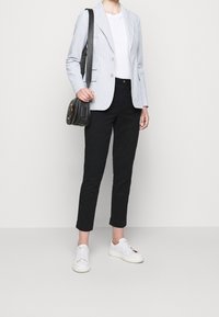 Ljusblårandig blazer, vit t-shirt, svarta slim-fit byxor och vita sneakers. Svart axelväska med detaljer i guld.