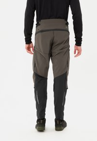 Heren outdoorbroek in donkergroen en zwart, met een slim fit, versterkte naden, zijritsen en zakken met een gestructureerd oppervlak.
