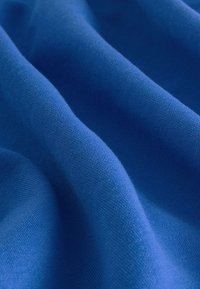 Modrá tkanina s jemnou pletenou textúrou, zobrazená v jemných záhyboch a vlnkách.