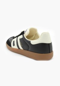 Czarne skórzane sneakersy z białymi teksturowanymi akcentami i paskami. Posiadają brązową gumową podeszwę oraz miękką wyściółkę wewnętrzną. Widoczne logo marki.