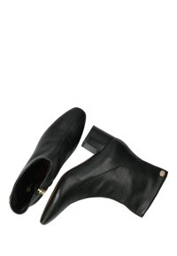 Botas de cuero negras hasta el tobillo con punta afilada, tacón medio cuadrado y detalle de logo en relieve. Textura suave con detalles de costura mínimos.