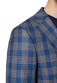 Niebieska marynarka w kratę z teksturowanej tkaniny z brązowymi i jasnoniebieskimi liniami. Wyróżnia się dopasowanym krojem i wyrazistym kołnierzem.